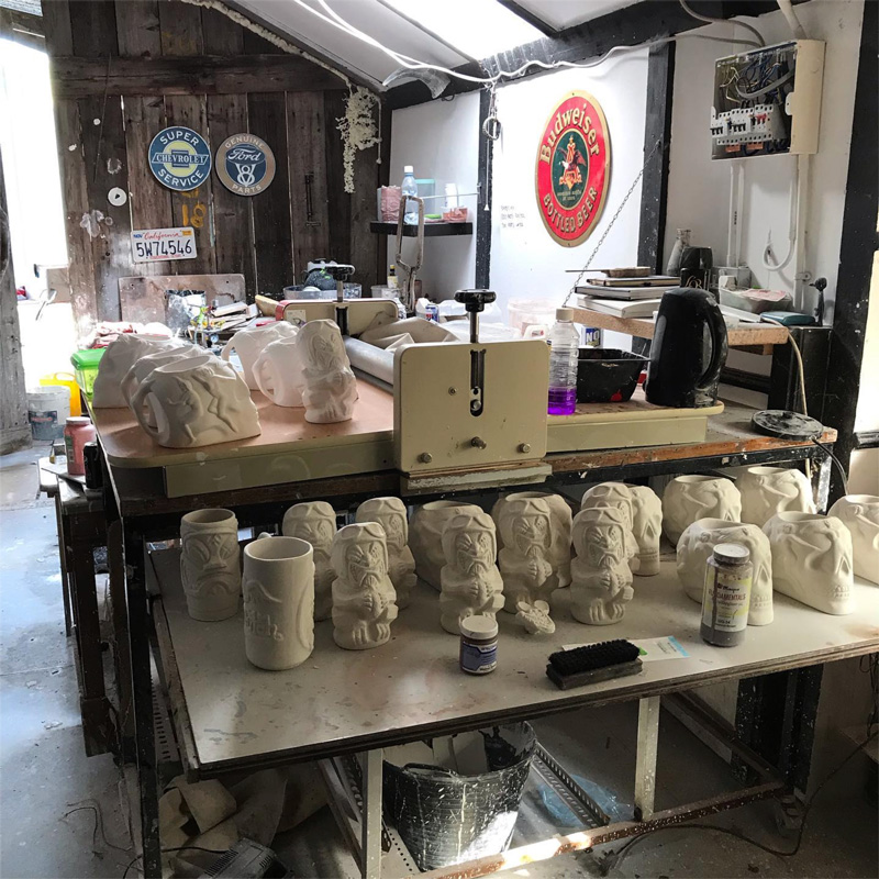 Tiki mugs on shelves in different stages of production